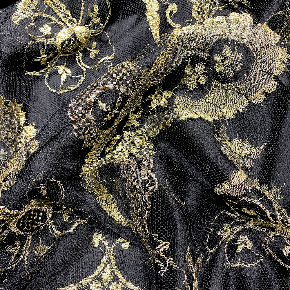 Calais lace gold laminette on a black background — Tissus en Ligne