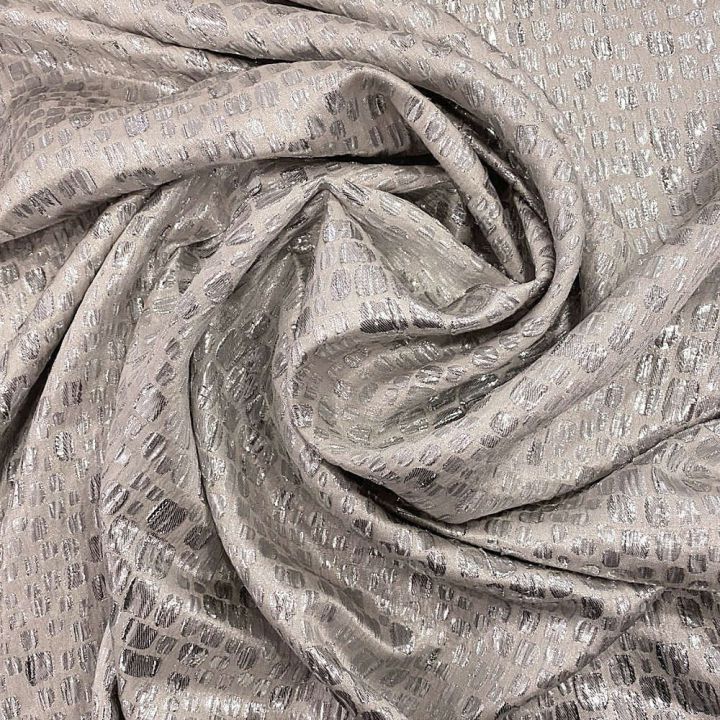 Silver scale silk lamé fabric on a beige background